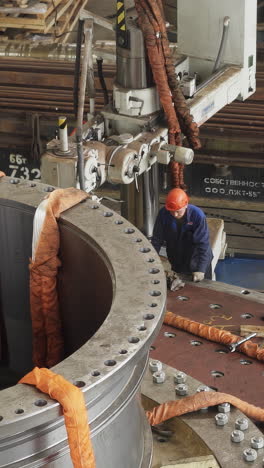 industrial worker repairing large metal parts on heavy machinery