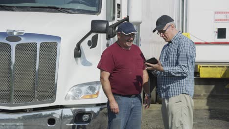 truck driver and shipping manager look at digital tablet.