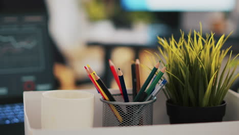 Focus-on-desk-belongings-in-modern-office-with-laptop-in-background,-close-up