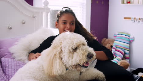 young teen girl petting pet dog on her bed