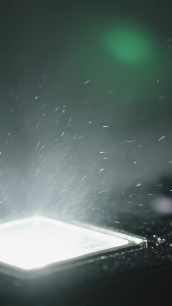 Vertical video: Square LED lifting dust after burst on bench with bezel and green bokeh, copy space