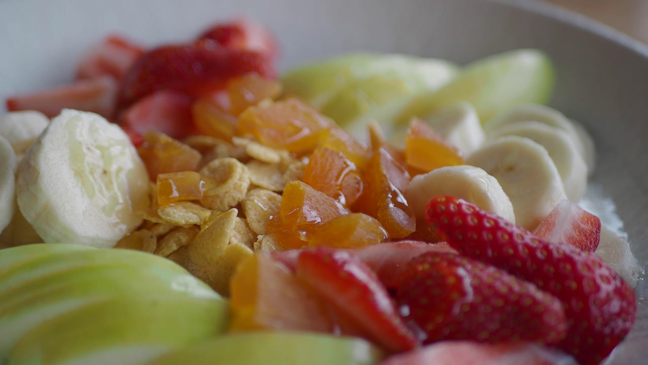 Vibrant Bowl of Fresh Fruit, Cereal, and Honey for Breakfast