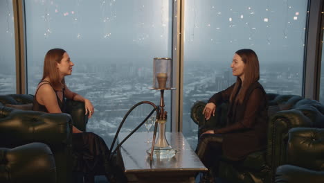 dos mujeres disfrutando de un narguile y champán con una vista de la ciudad
