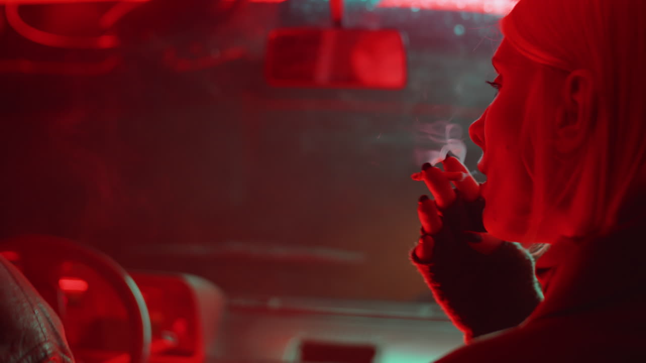 젊은 여성과 남자가 차에서 담배를 피우고 있습니다.