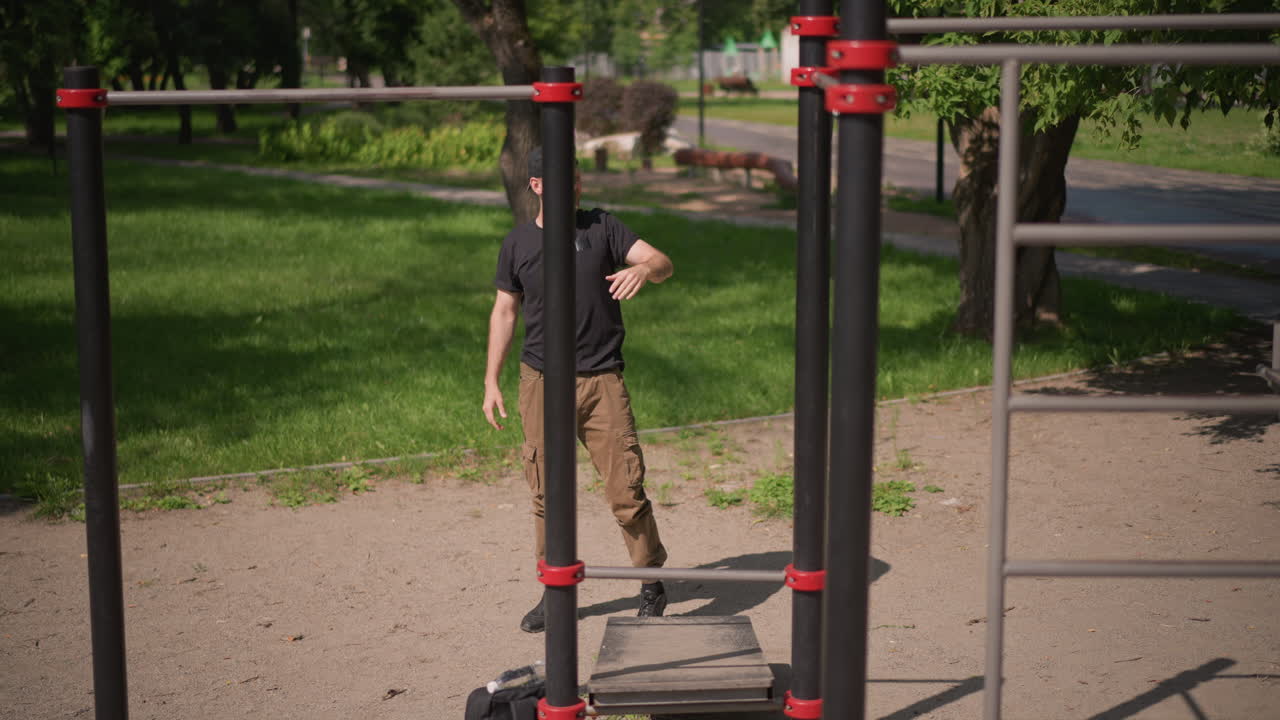 White Man Entering Outdoor Calisthenics Park, Walking Between Bars, Scanning Equipment, Lighthearted Anticipation, Casual TShirt And Cap, Preparing To Start Street Workout Routine