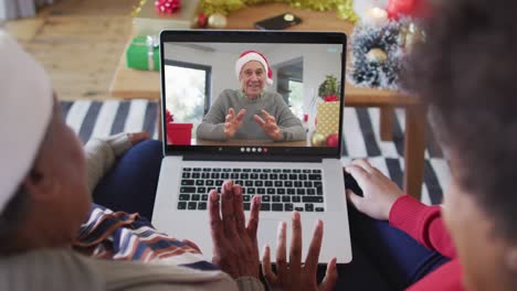 Madre-E-Hija-Afroamericanas-Usando-Una-Computadora-Portátil-Para-Una-Videollamada-Navideña-Con-Un-Hombre-En-La-Pantalla