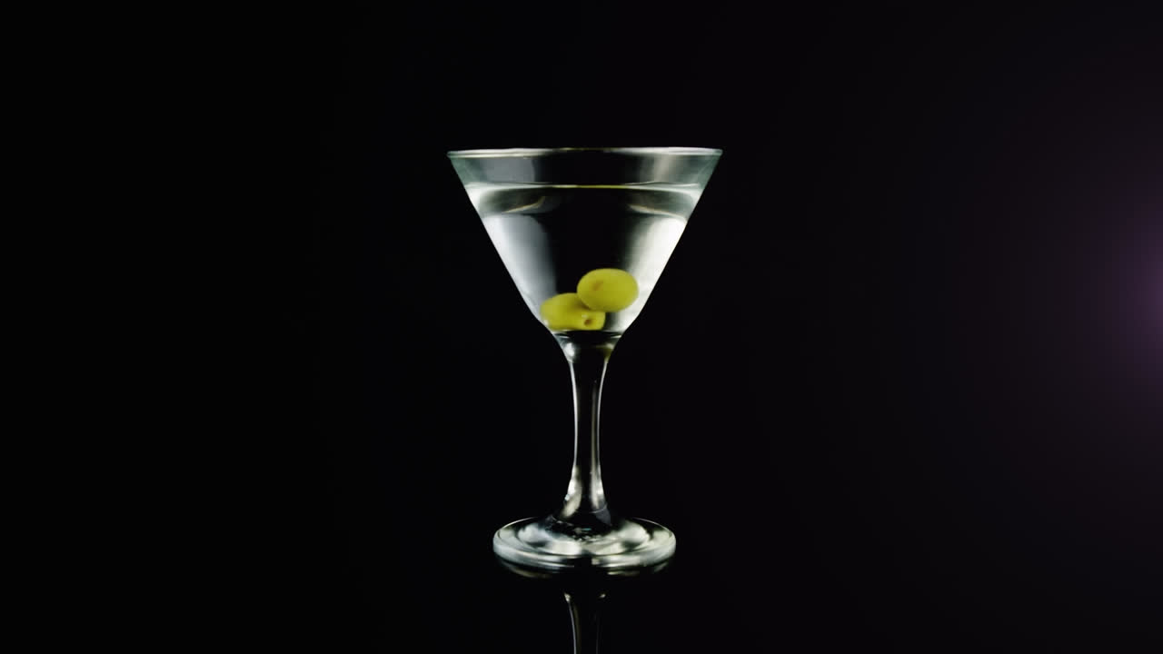 animación de formas púrpuras sobre una bebida con aceitunas sobre fondo negro.