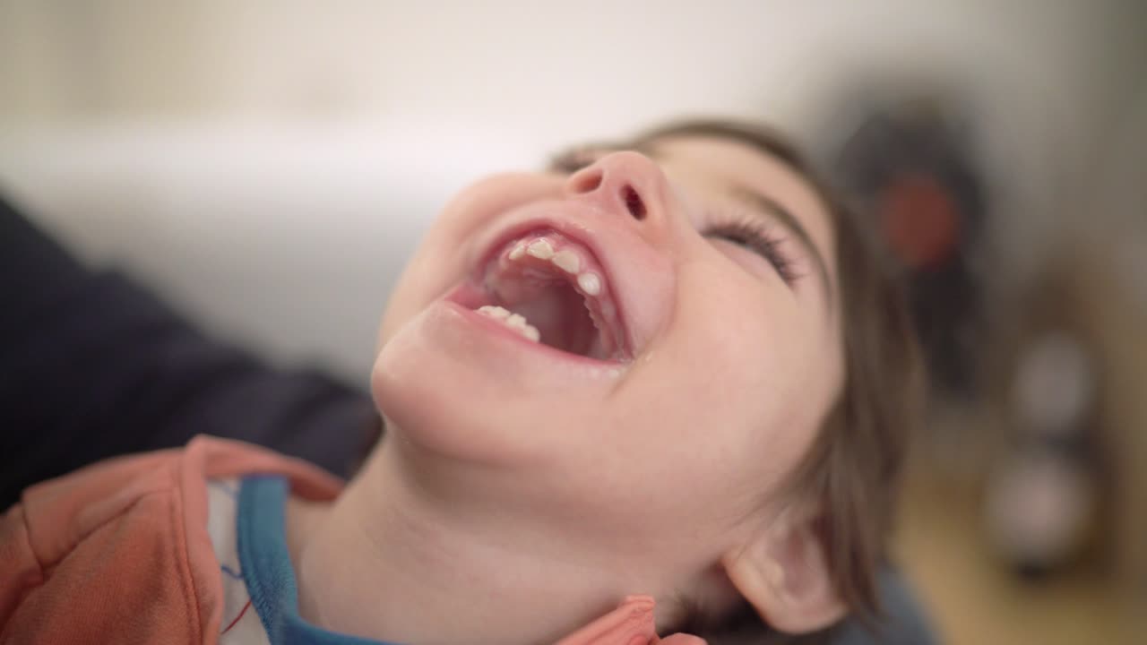 Little girl with special needs cerebral palsy is having fun, laughing, giggling and smiling in her fathers arms in their home