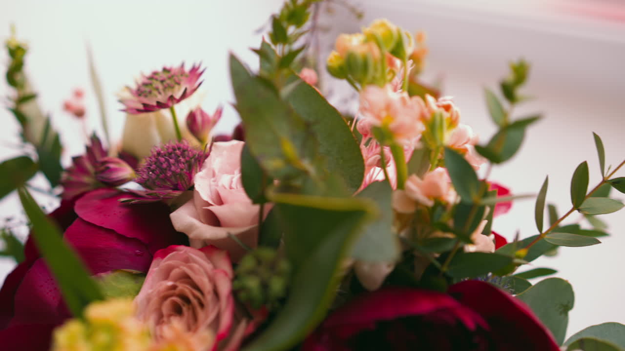 Bouquet con fiori aromatici e foglie verdi su un tavolo.