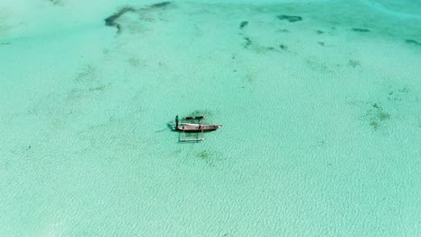 aerial view of a fisherman sails on a wooden boat on clear blue water along a tropical exotic beach in africa