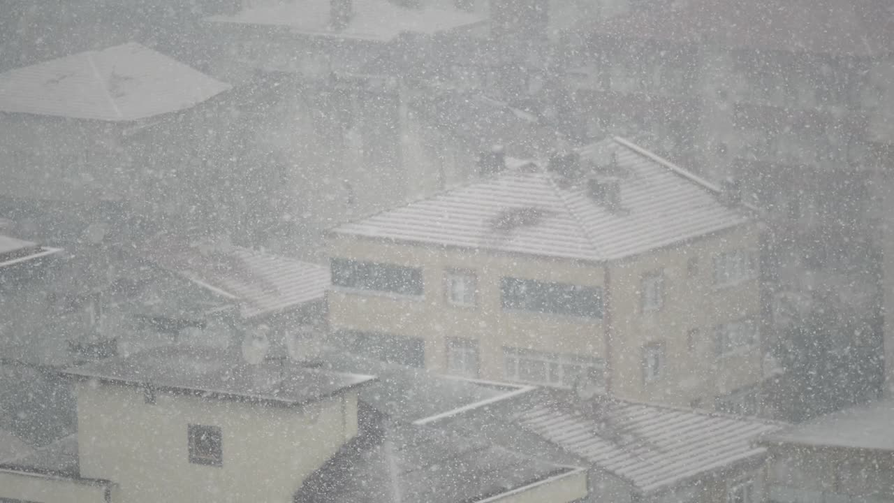 Snowfall over city rooftops