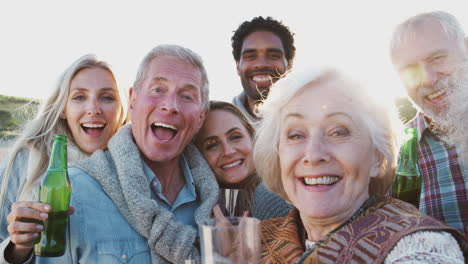 retrato de una familia adulta de varias generaciones haciendo un brindis con alcohol en vacaciones de playa de invierno