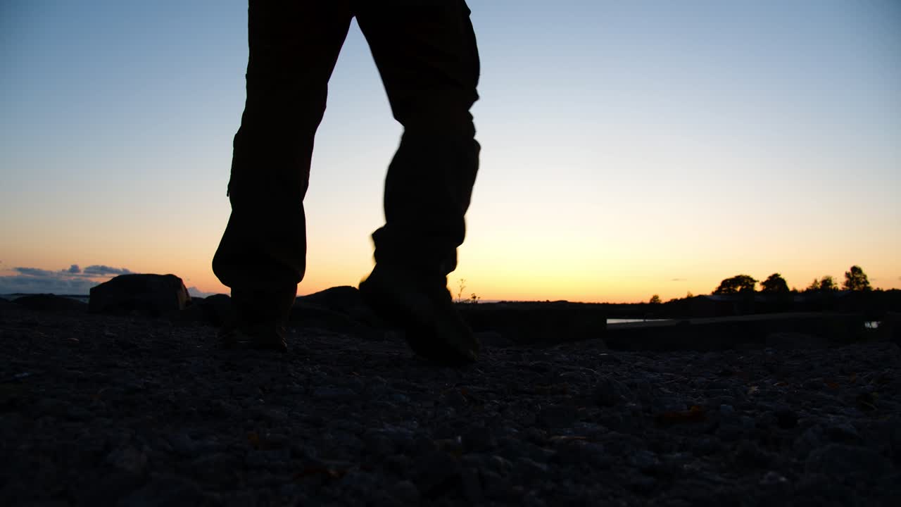Men's legs walking on the beach at sunset