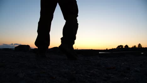 las piernas de los hombres caminando por la playa al atardecer