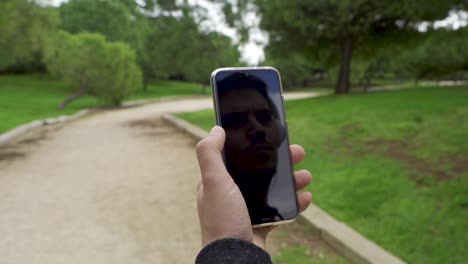 reflejo del hombre con cascos en el móvil, mira el cielo y luego toca la pantalla