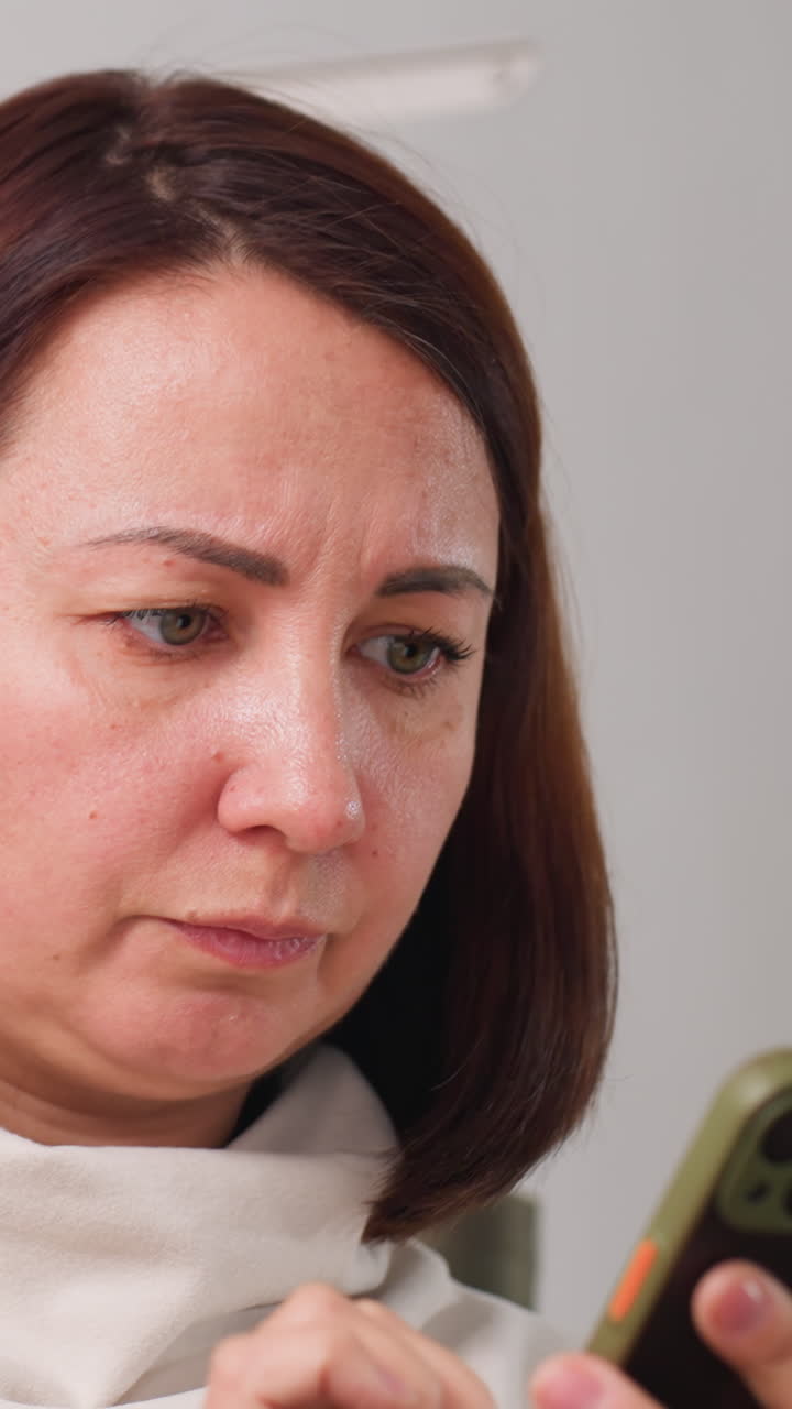 freelancer concentrado de piel blanca revisando una factura en el teléfono, en un entorno de oficina en casa, pulsando en la app de pago con expresión concentrada, manos con la pantalla, ambiente de flujo de trabajo digital moderno