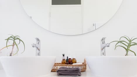 Close-up-of-washbasin,-accesories-and-mirror-in-bathroom,-slow-motion