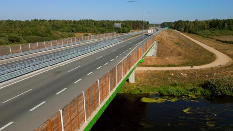 trucks on expressway s8 road through forested land, static shot