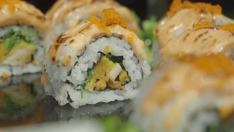 close-up of delicious japanese sushi rolls topped with sauce and roe