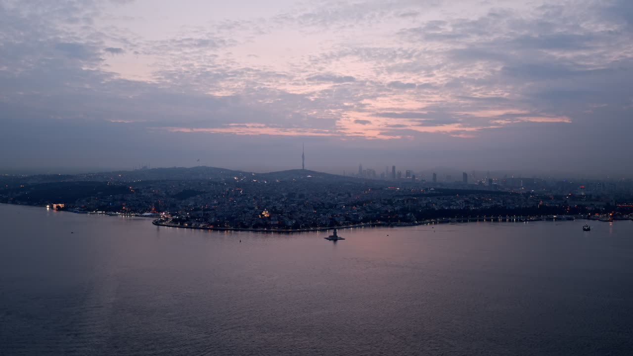 Dusk settles over Istanbul as soft pink clouds reflect on the Bosphorus, with city lights slowly emerging across the hills and skyline