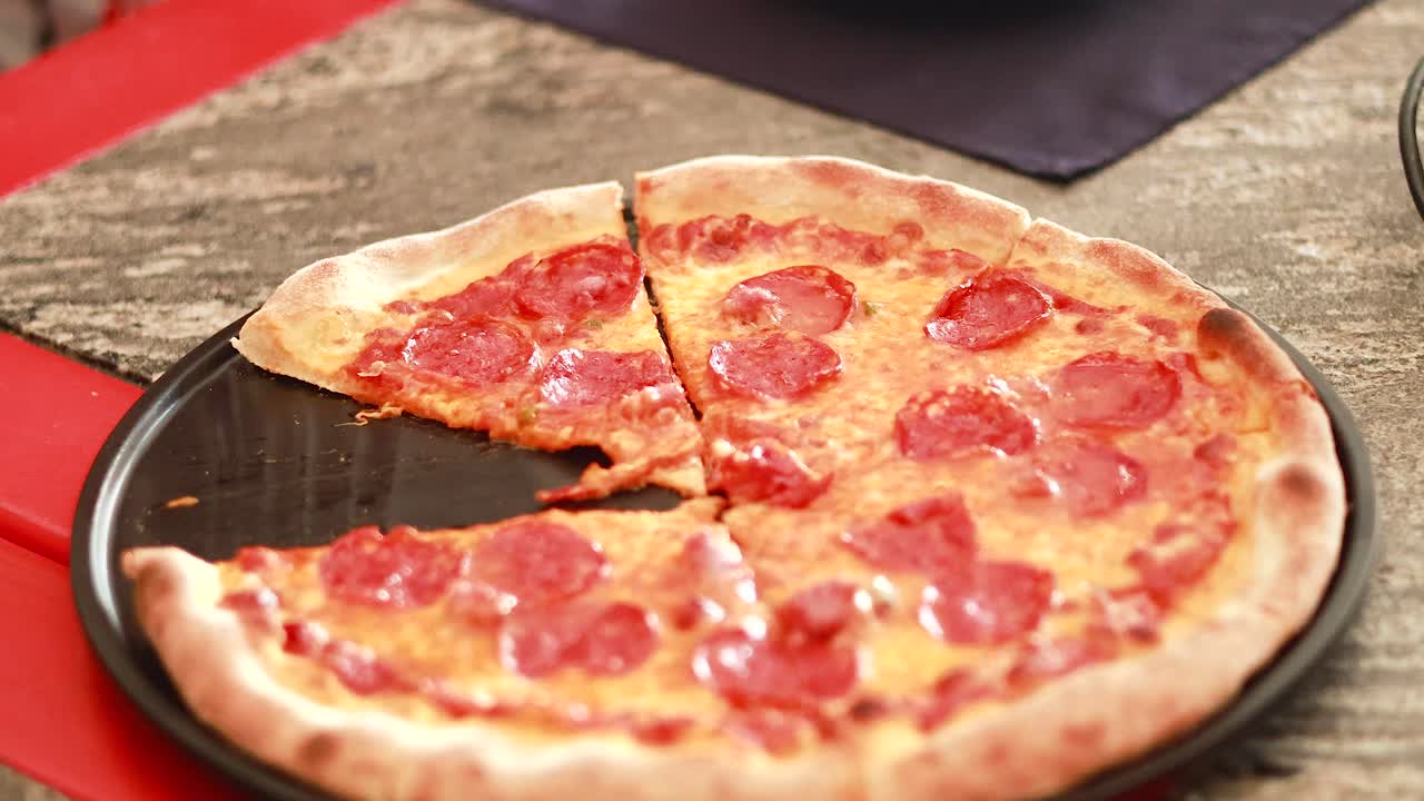 테이블 위에 신선하게 구운 페페로니 피자를 잘라내는 것