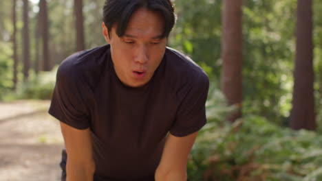 close up of tired mid adult man exercising doing work out outdoors running along track through forest stopping to catch breath shot in real time