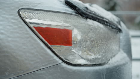 detailed close-up of a car's frosted taillight covered with ice and snow, highlighting intricate ice patterns and the chilling effect on vehicle surfaces during winter