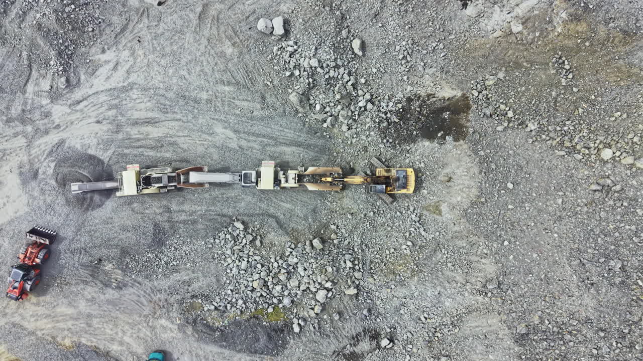 Granite quarry operation showing machinery extracting rock and stone at a construction site in broad daylight
