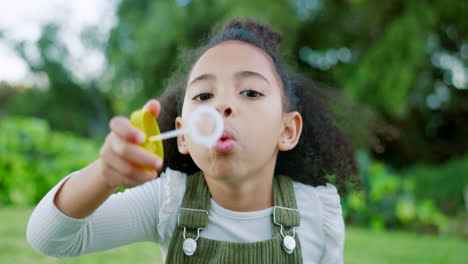 black girl kid blowing soap bubbles in park