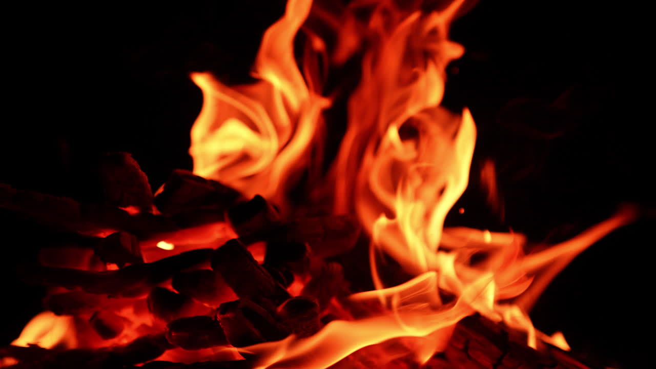 Pezzi di legno bruciano nel piccolo falò. Vista ravvicinata di un falò nella notte buia.