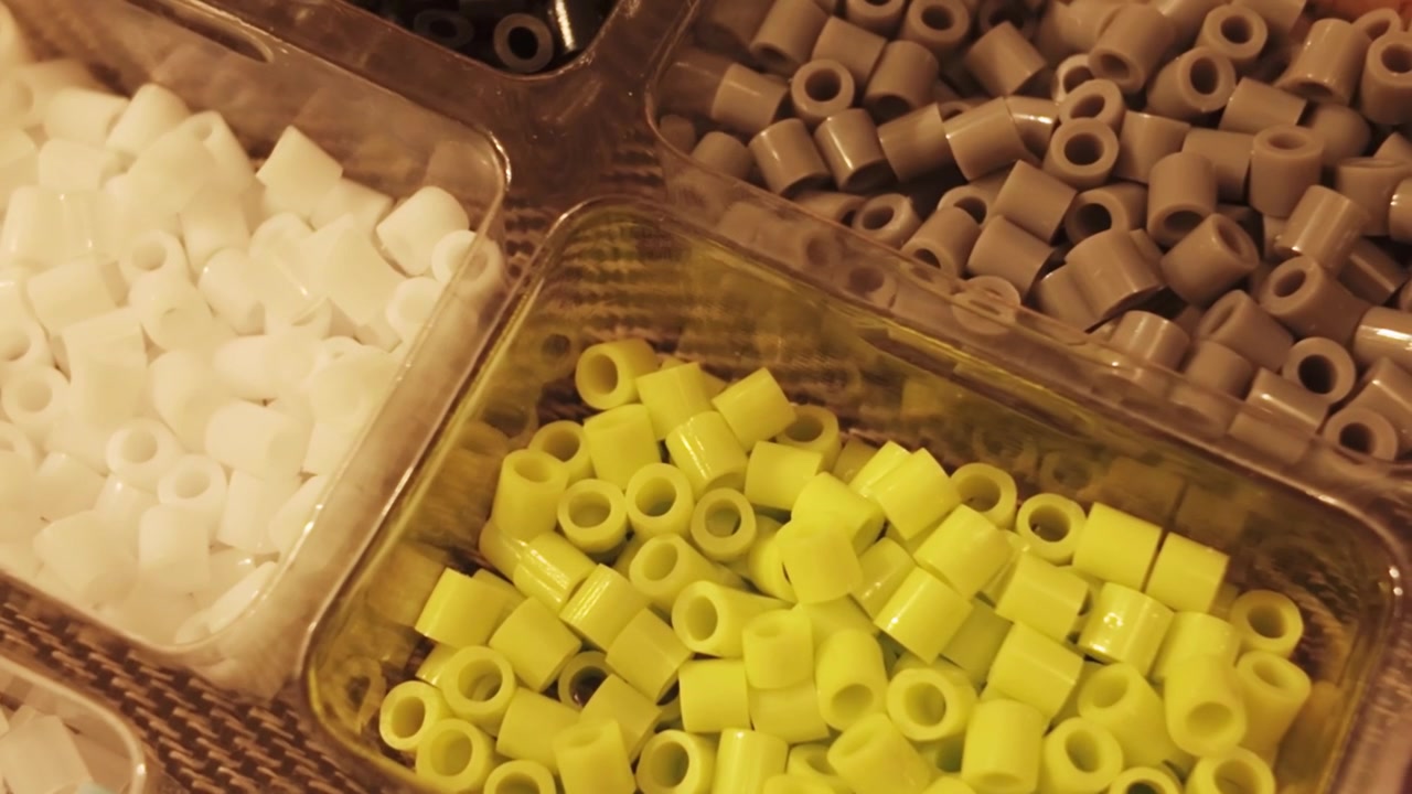 Cylindriske perler udstillet i organiserede bakker til fremstilling af håndlavede accessories