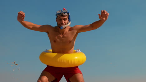 Man-wearing-flippers-and-rubber-ring-at-the-beach