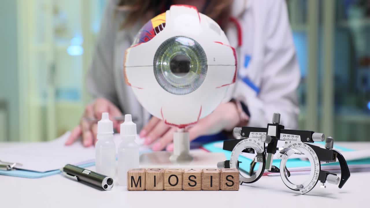 Miosis Word with Eye Model and Optometry Tools on Doctor's Desk