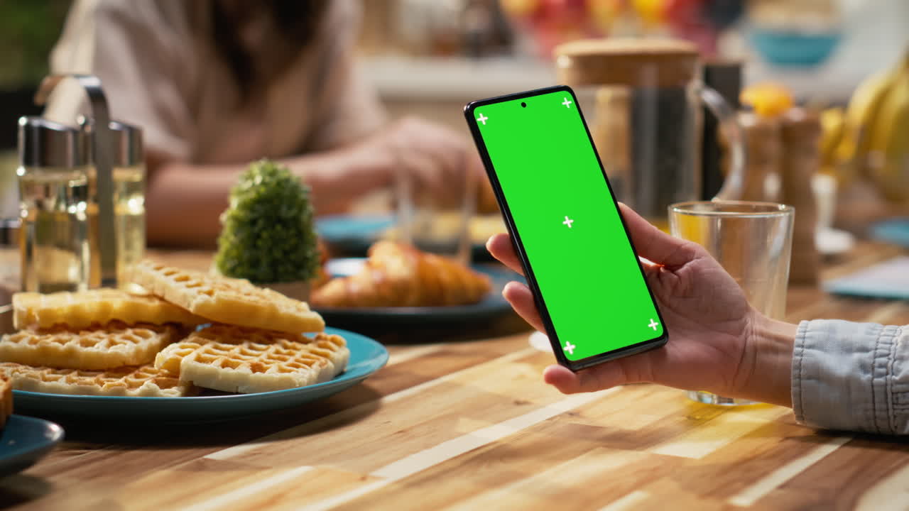 Vertical green screen smartphone held by mom serving breakfast with daughter