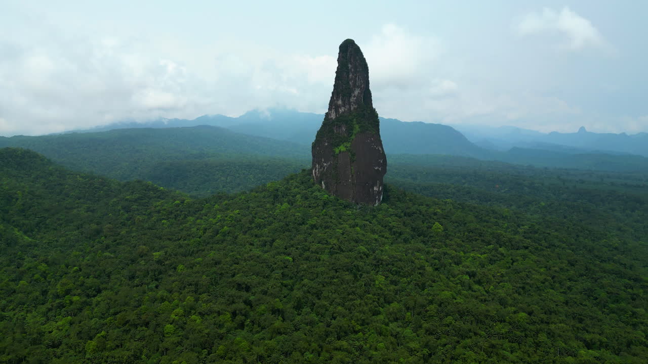 Drone tilting toward the towering Pico Cao Grande needle peak in Sao Tome