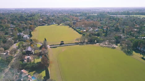 AERIAL---Beautiful-green-fields-at-a-golf-club,-wide-shot-backwards