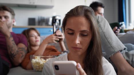 group of friends using mobile phones at the home party