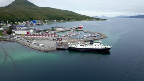 Toma-Aérea-Orbital-Del-Puerto-De-Botnhamn-En-Senja-Con-Una-Fila-De-Autos-Y-Campistas-Esperando-Para-Abordar-El-Ferry.