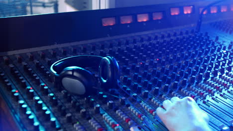 a male sound engineer pressing buttons on a mixer. the man is an audio technician in a professional recording studio operating a mixing desk