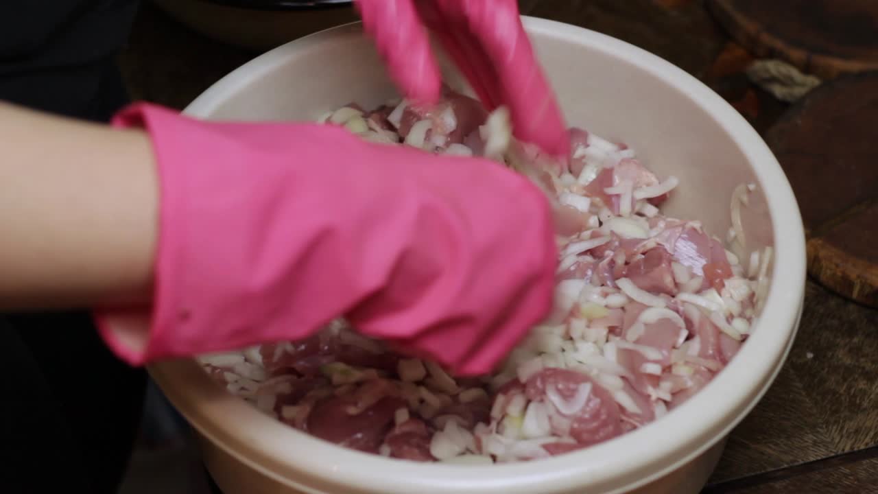 повар смешивает шашлык из сырой курицы в миске с луком и чесноком, чтобы замариновать ее