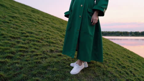 close-up of white sneakers on a grassy hill at sunset