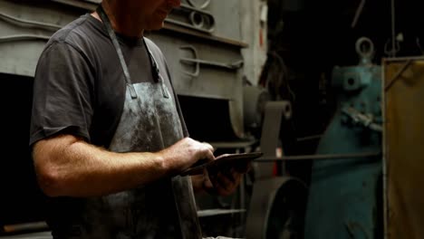 Blacksmith-using-digital-tablet-in-workshop-4k