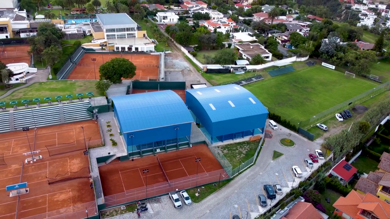 Esta tomada de drone com movimento pull-out revela o complexo esportivo de estrutura metálica em Quito, Equador. A tomada se expande para mostrar toda a estrutura, destacando o edifício concluído e seus arredores