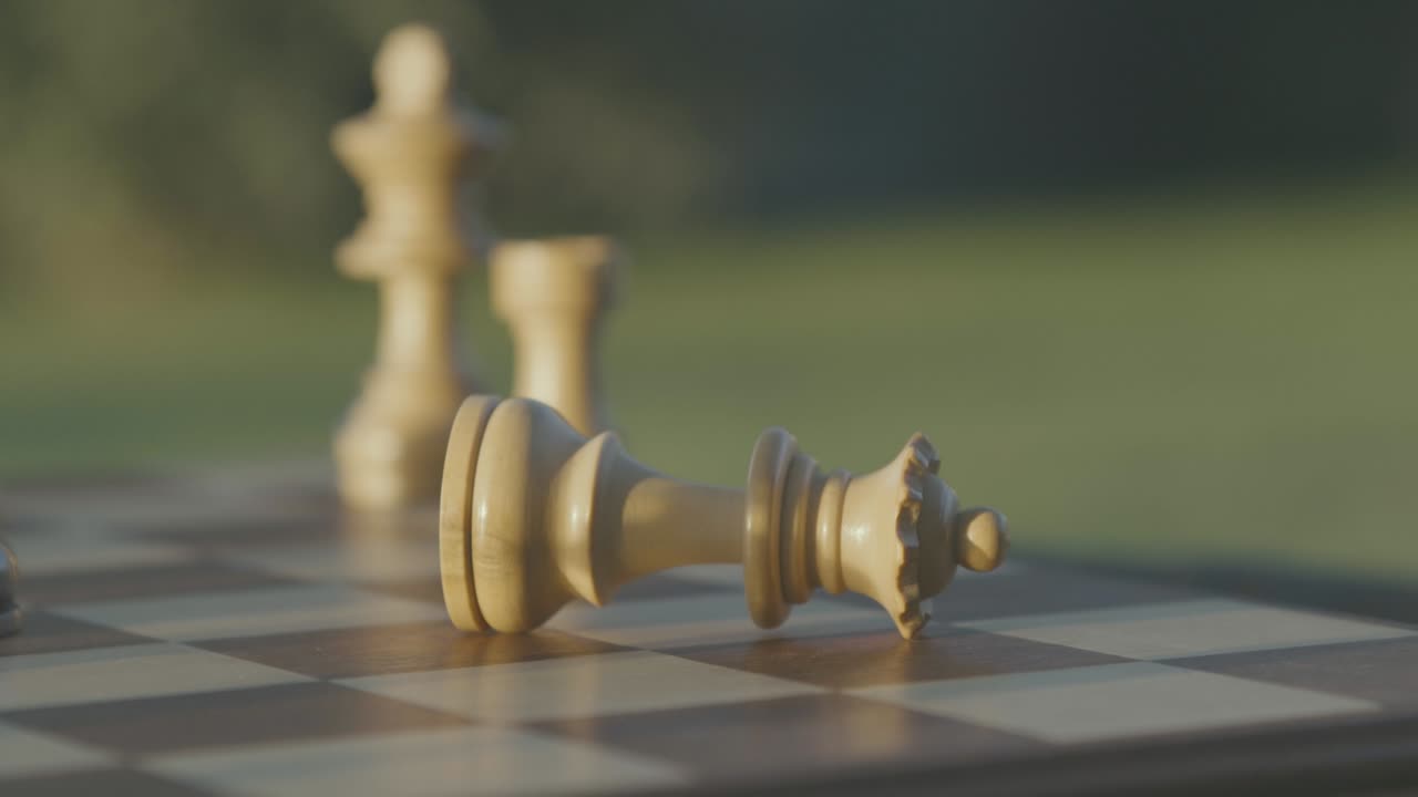 A hand takes the white queen and drops it, chess game
