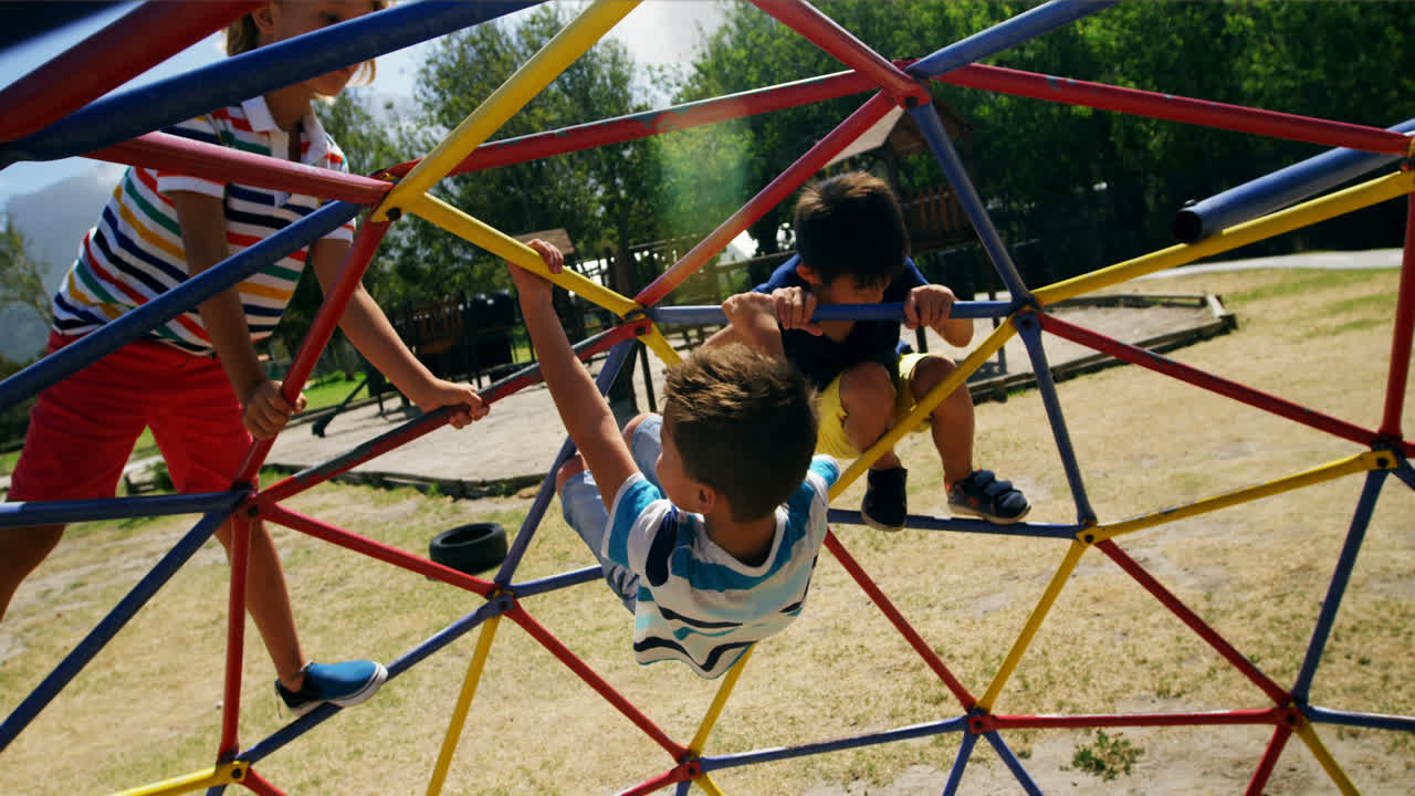 Niños escolares jugando en una cúpula trepadora en el patio de recreo.