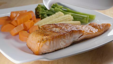 Slow-Motion-Close-Shot-of-Pouring-a-White-Sauce-on-a-Pan-Fried-Salmon-Fillet-with-Vegetables-on-a-White-Dinner-Plate