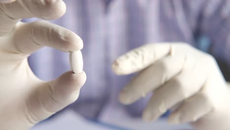 doctor holding a pill in sterile gloves