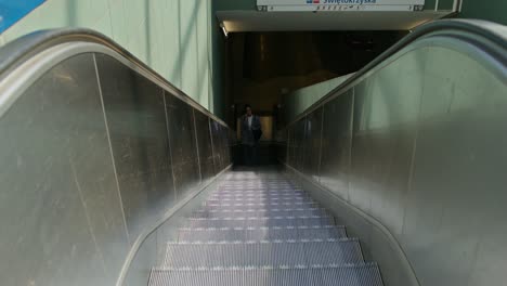 woman walking up a moving staircase in a metro station