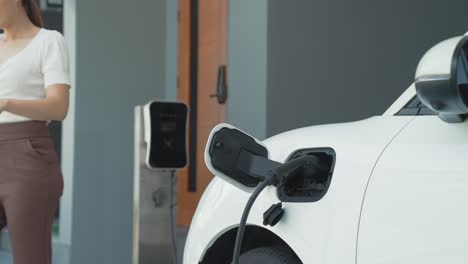 progressive woman unplugs the electric vehicle's charger at his residence.