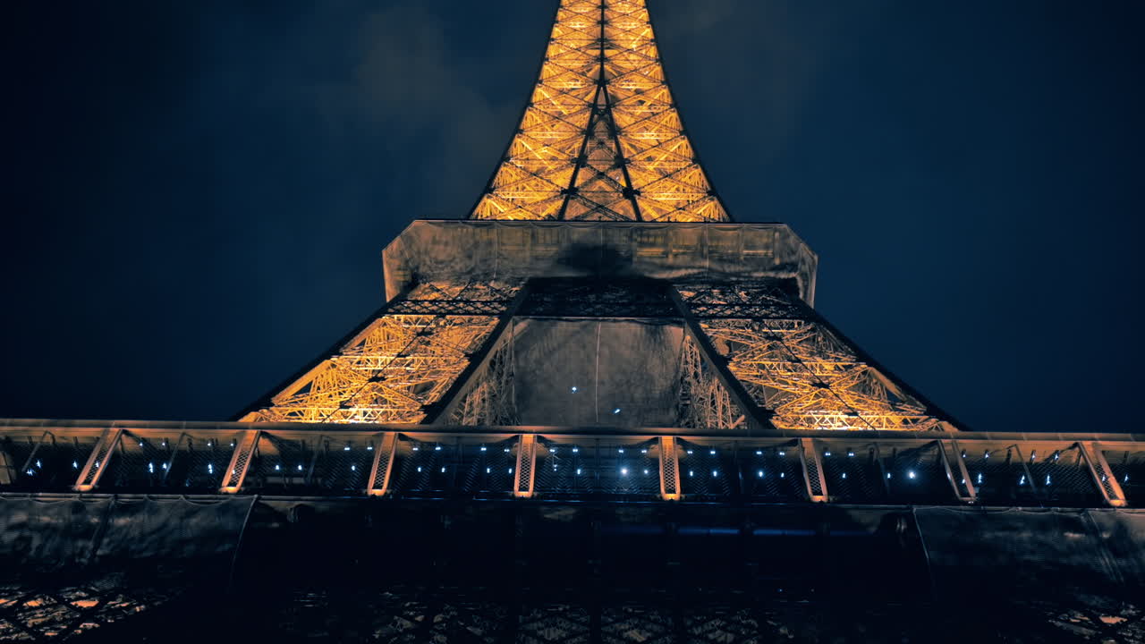 Close view of the illuminated Eiffel Tower in Paris at night, France. Multiple nightlights, bottom view